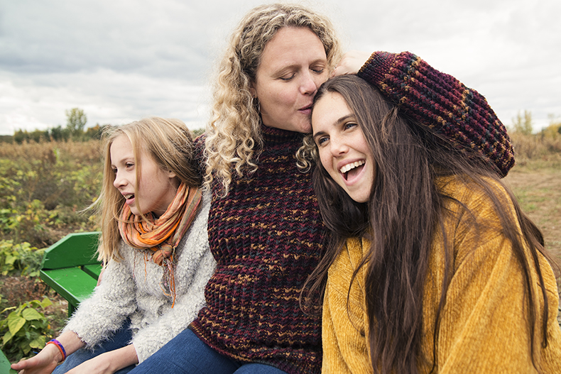 Mother with teenage daughters strolling in trailer in field